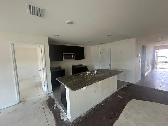 A kitchen features dark cabinets, a granite-topped island, and unfinished flooring in an open space — 24528 NW 7TH LANE, NEWBERRY, FL