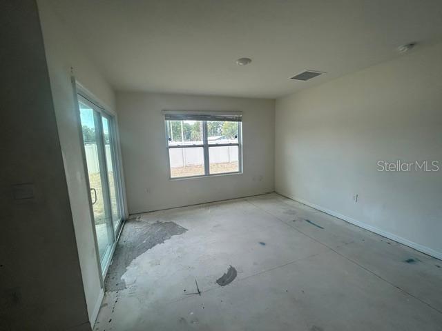 An unfinished room features concrete floors, a sliding glass door, and a single window — 24528 NW 7TH LANE, NEWBERRY, FL