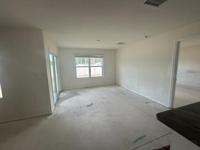 An unfinished room with concrete floors, a sliding glass door, and a window — 24528 NW 7TH LANE, NEWBERRY, FL