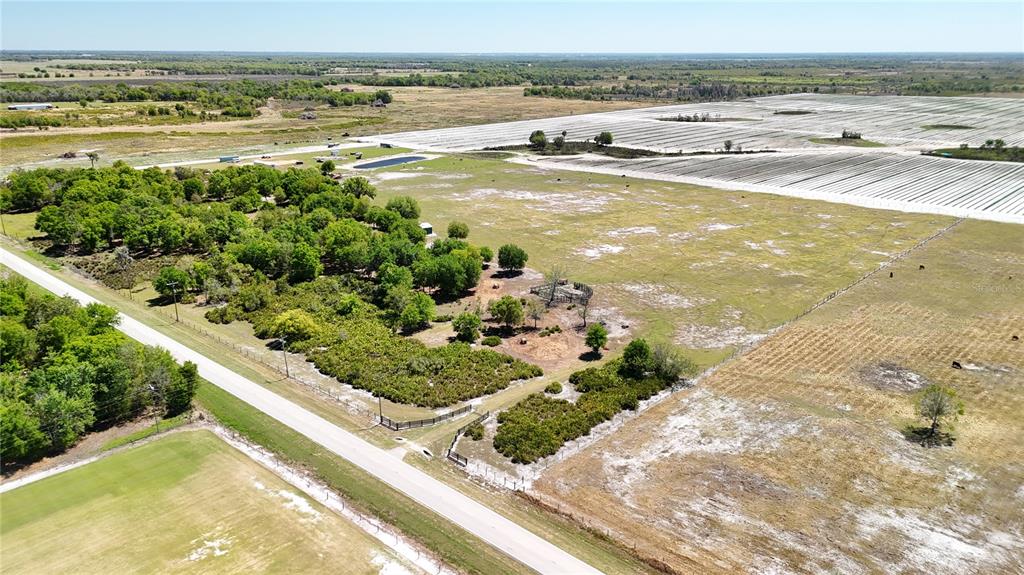 An aerial view shows a rural property with a road, pasture, trees, and fenced areas — AVON PARK CUTOFF ROAD, FORT MEADE, FL