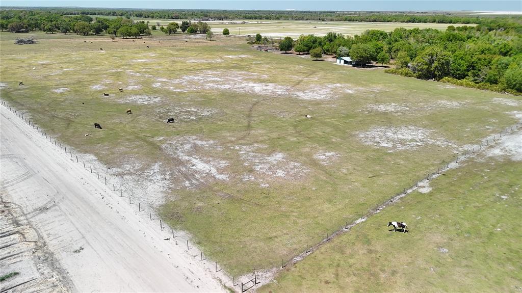 An aerial view shows a fenced pasture with grazing cattle and a small building nearby — AVON PARK CUTOFF ROAD, FORT MEADE, FL