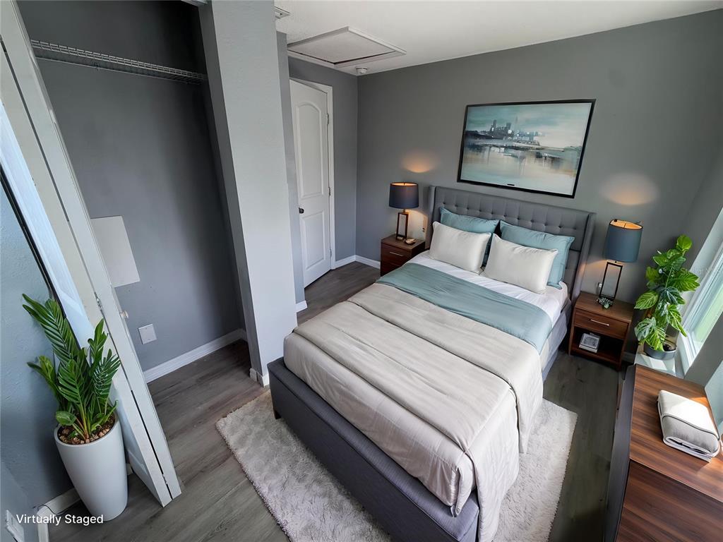 A virtually staged bedroom features a gray upholstered bed, two nightstands, and wood-look flooring — 1208 17TH ST N, ST PETERSBURG, FL