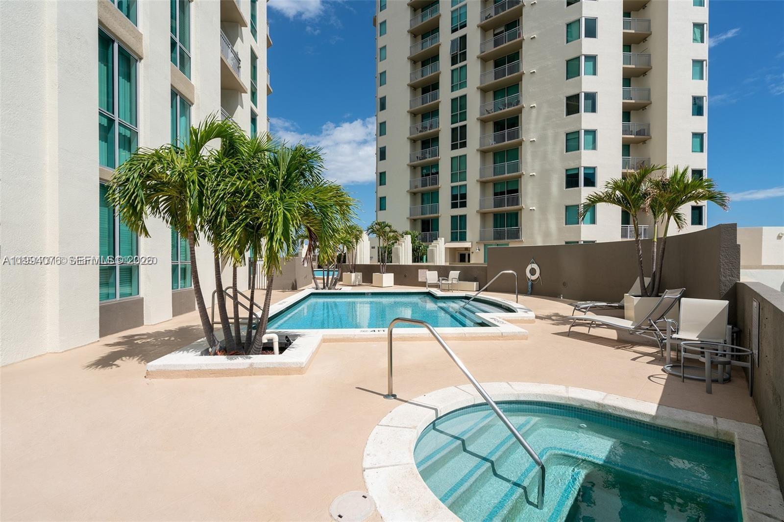 An outdoor pool and hot tub area sits between two tall residential buildings — 9066 SW 73rd Ct # 1202, Miami FL 33156, MIAMI, FL