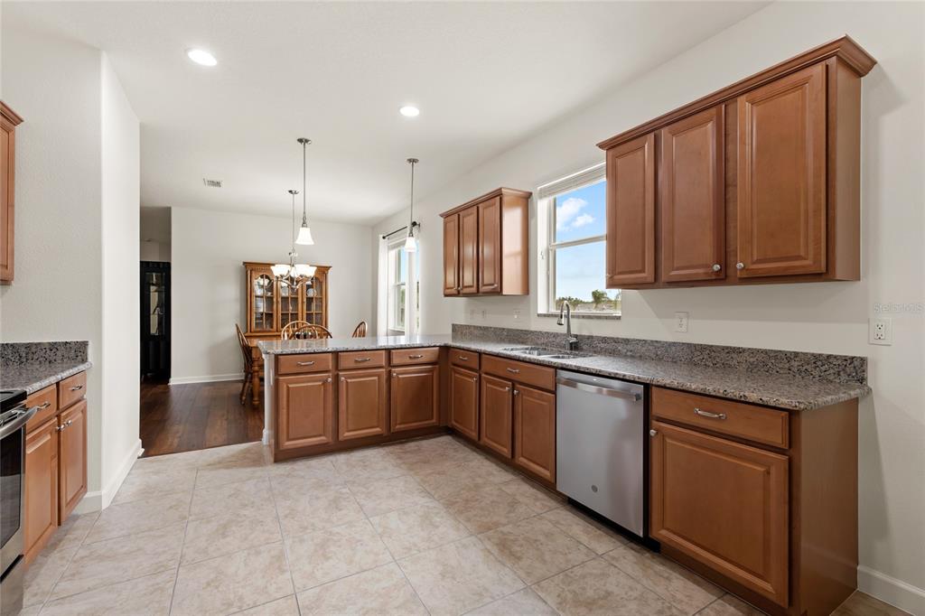 A kitchen with wood cabinets, granite countertops, stainless steel appliances, and tile flooring — 3801 SERENA LANE, CLERMONT, FL
