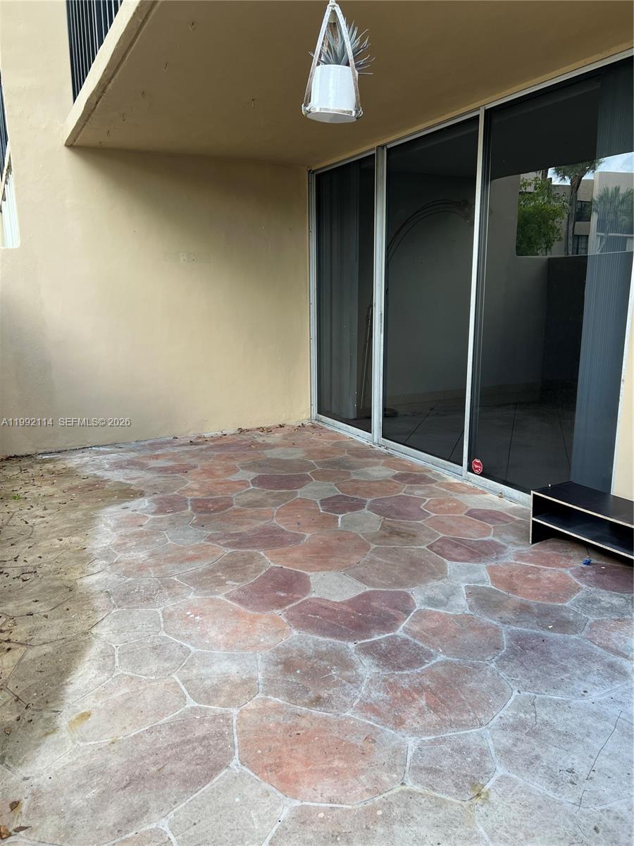 A patio features a stone-patterned concrete floor and a sliding glass door — 10845 SW 112th Ave # 107, Miami FL 33176, MIAMI, FL