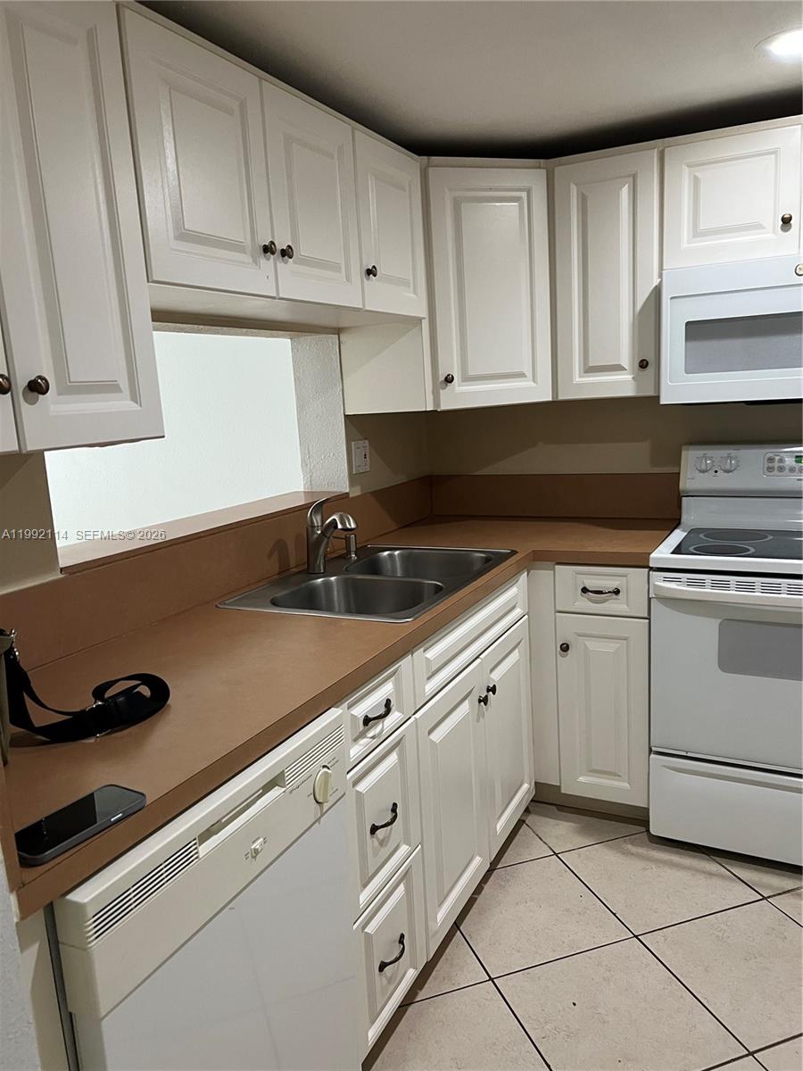 A kitchen features white cabinets, a brown countertop, a double sink, and white appliances — 10845 SW 112th Ave # 107, Miami FL 33176, MIAMI, FL