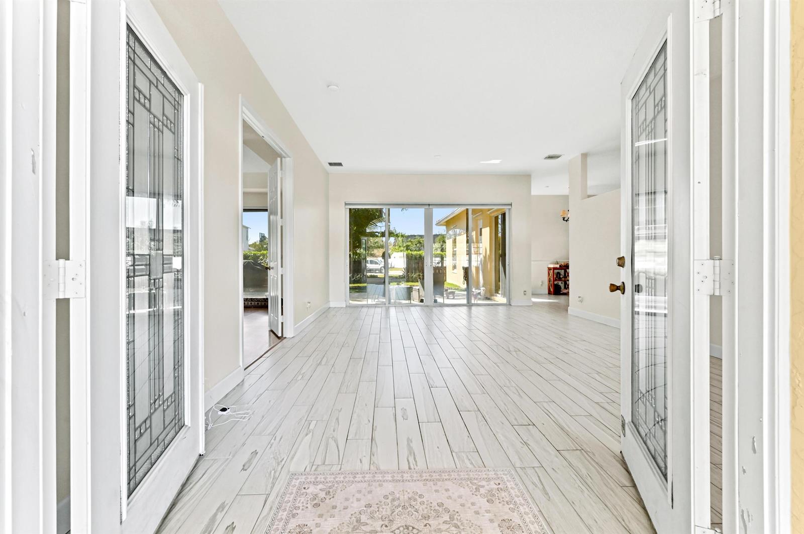 An interior view of a bright room with white wood-look tile flooring and glass doors — 1791 Pierce Drive, FL 33460, FL