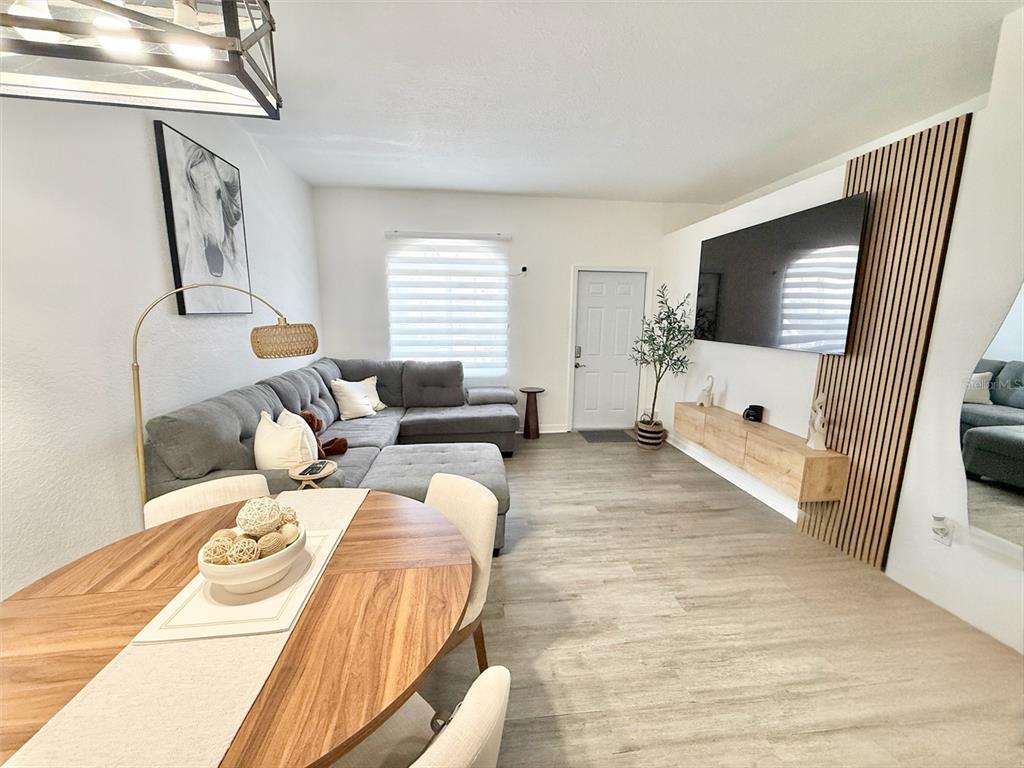 A living room features a grey sectional sofa, a wall-mounted television, and a dining area — 22102 INDIAN CREEK DRIVE UNIT 1, KISSIMMEE, FL