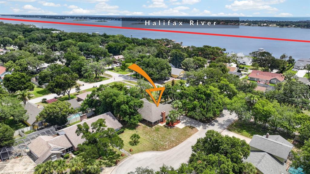 An aerial view shows a residential house with a chimney surrounded by trees near water — 1510 N BEACH STREET, ORMOND BEACH, FL