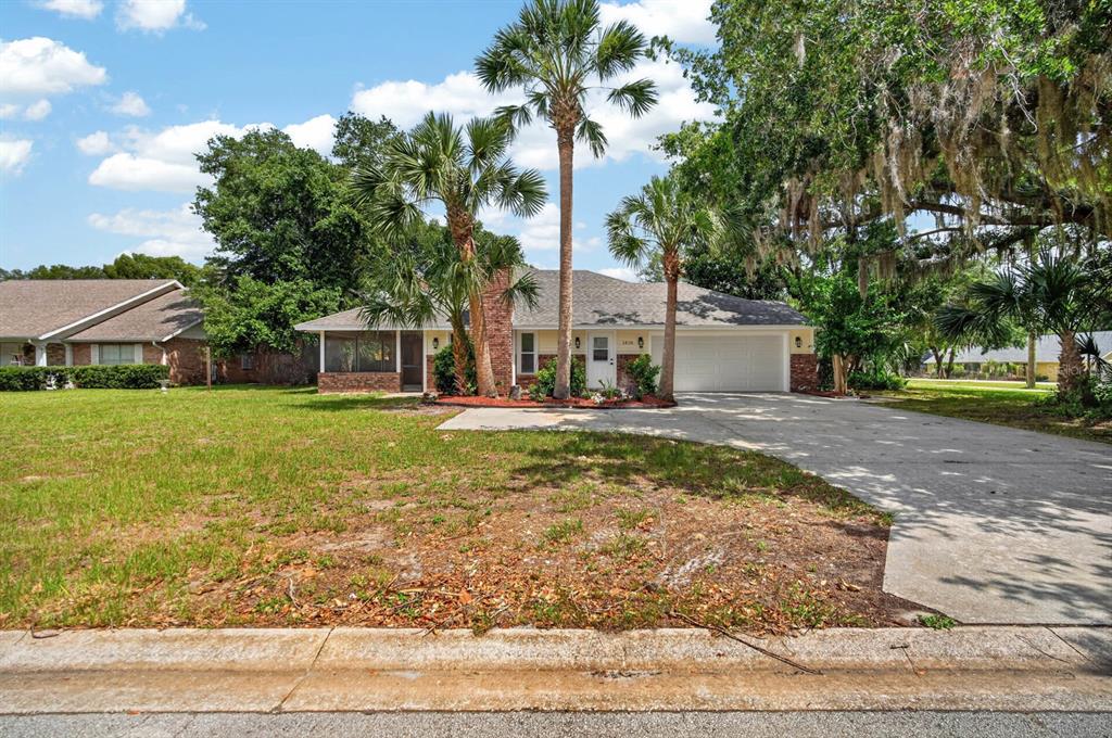 A single-story house with a brick chimney, palm trees, and a concrete driveway — 1510 N BEACH STREET, ORMOND BEACH, FL