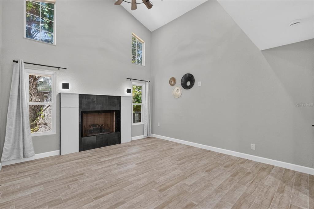 A living room features a high vaulted ceiling, tile flooring, and a tiled fireplace surround — 1510 N BEACH STREET, ORMOND BEACH, FL