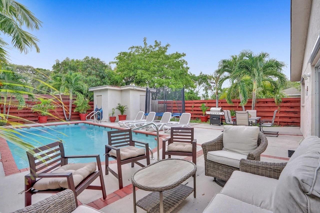 A backyard patio features a swimming pool, outdoor furniture, a grill, and a trampoline — 208 SW 2nd Ave, Hallandale Beach FL 33009, HALLANDALE BEACH, FL