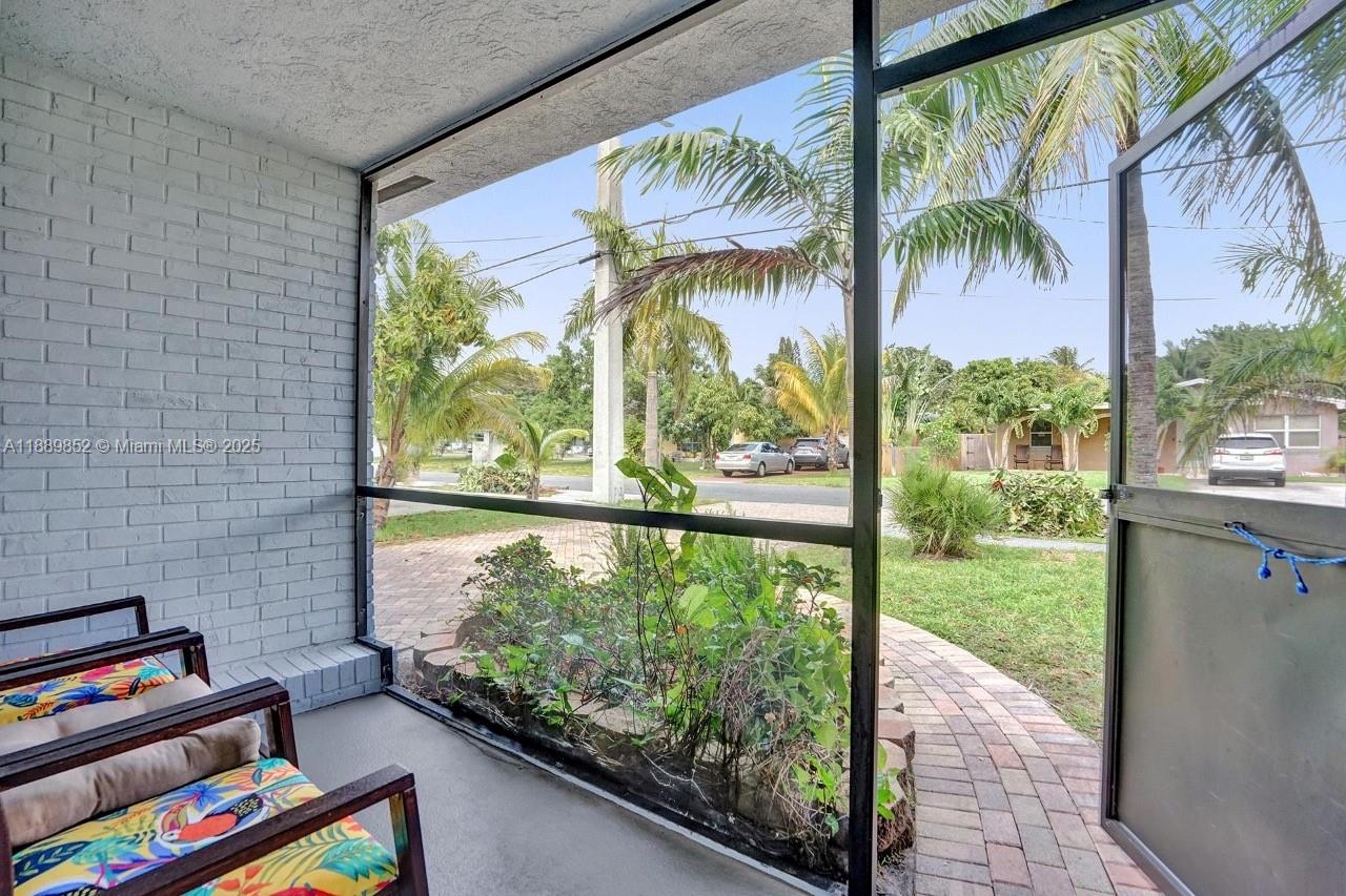 A screened-in porch with a brick wall overlooks a paved walkway and a grassy yard — 208 SW 2nd Ave, Hallandale Beach FL 33009, HALLANDALE BEACH, FL