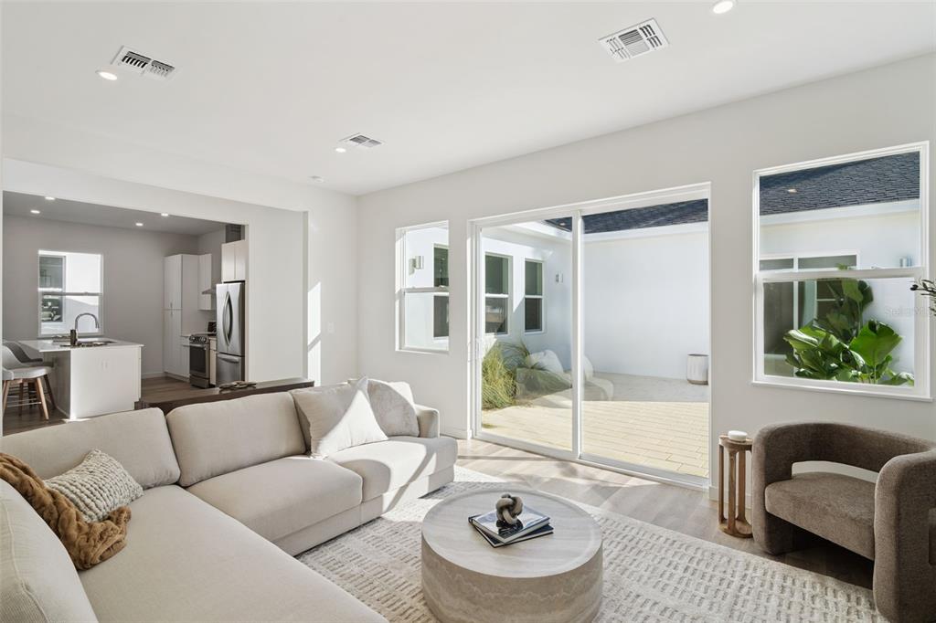 A living room with a sectional sofa, round coffee table, and sliding doors to a patio — 447 SKYFIELD COURT, LADY LAKE, FL