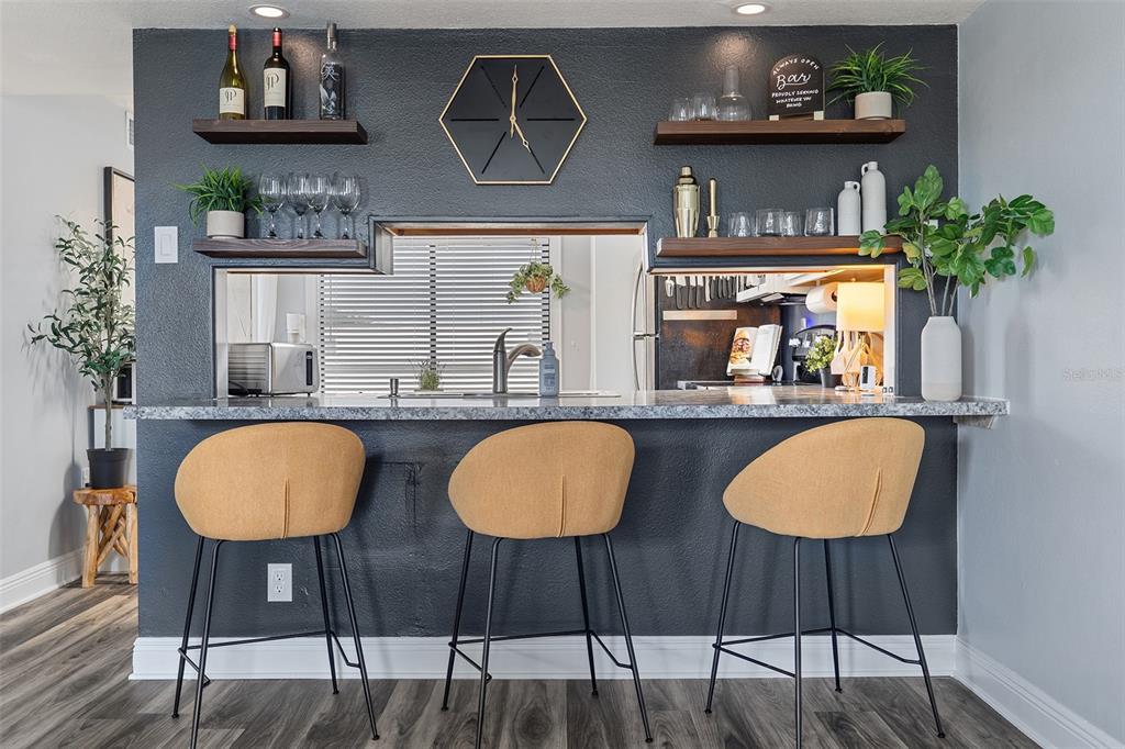 A kitchen pass-through window with a bar counter, three stools, and dark accent walls — 200 INTERNATIONAL DR UNIT 716, CAPE CANAVERAL, FL