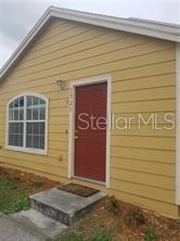 A yellow house exterior features a red front door and a white-framed window — 1325 WASHINGTON PALM LOOP, DAVENPORT, FL