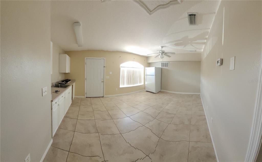A kitchen and living area with tile flooring, white cabinets, and a white refrigerator — 1325 WASHINGTON PALM LOOP, DAVENPORT, FL