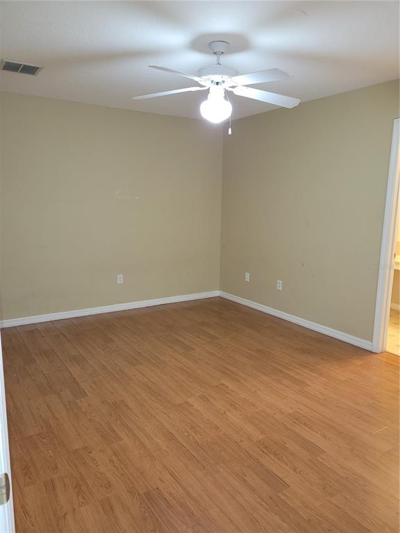 An empty bedroom features tan walls, wood-look flooring, and a white ceiling fan — 1325 WASHINGTON PALM LOOP, DAVENPORT, FL