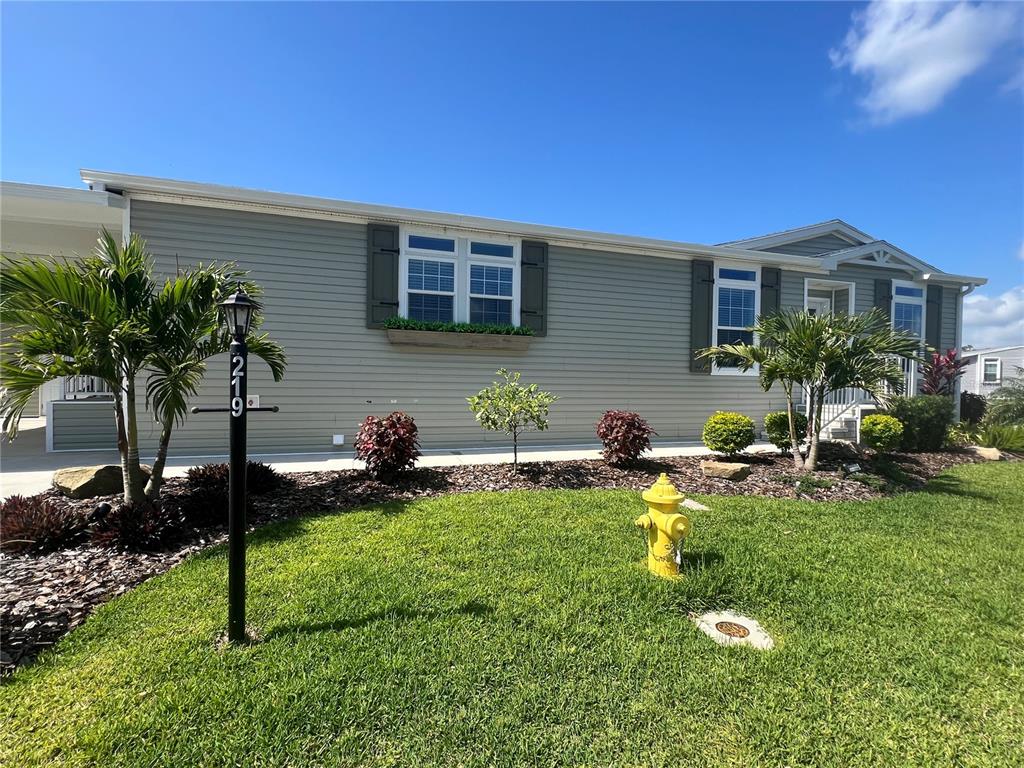 The exterior of a light green manufactured home features a fire hydrant and palm trees — 12116 SW CR 769 SW COUNTY ROAD 769 UNIT 219, LAKE SUZY, FL