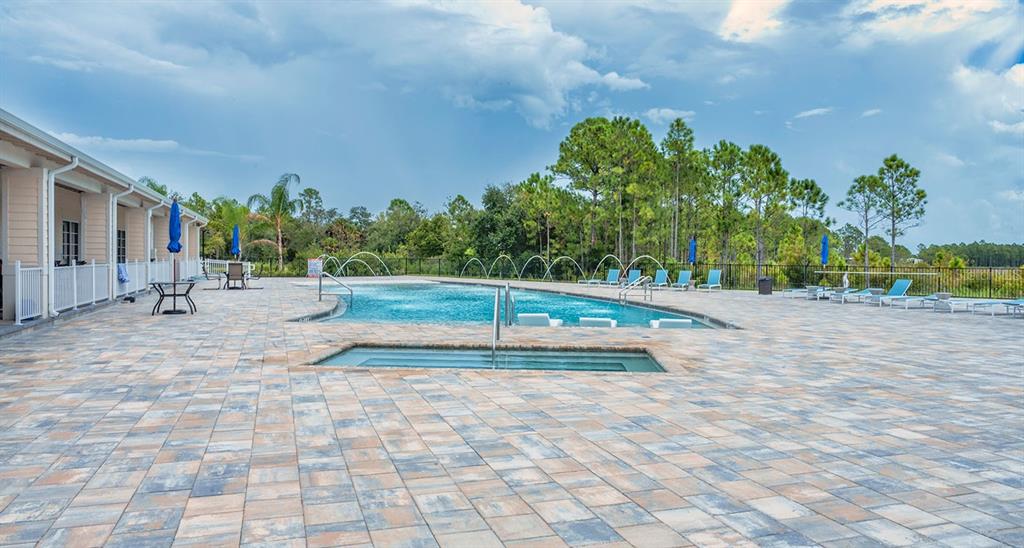 A swimming pool and hot tub sit on a large paved patio beside a building — 12116 SW CR 769 SW COUNTY ROAD 769 UNIT 219, LAKE SUZY, FL