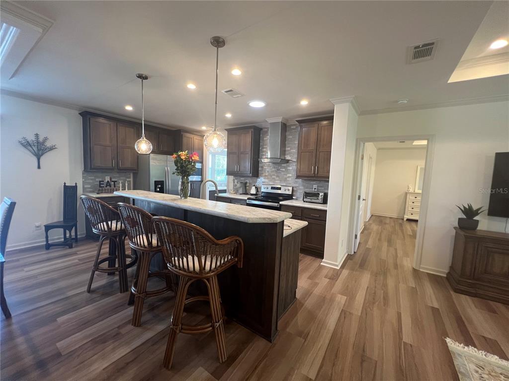 A kitchen features dark wood cabinets, a stone-topped island with bar stools, and wood-look flooring — 12116 SW CR 769 SW COUNTY ROAD 769 UNIT 219, LAKE SUZY, FL