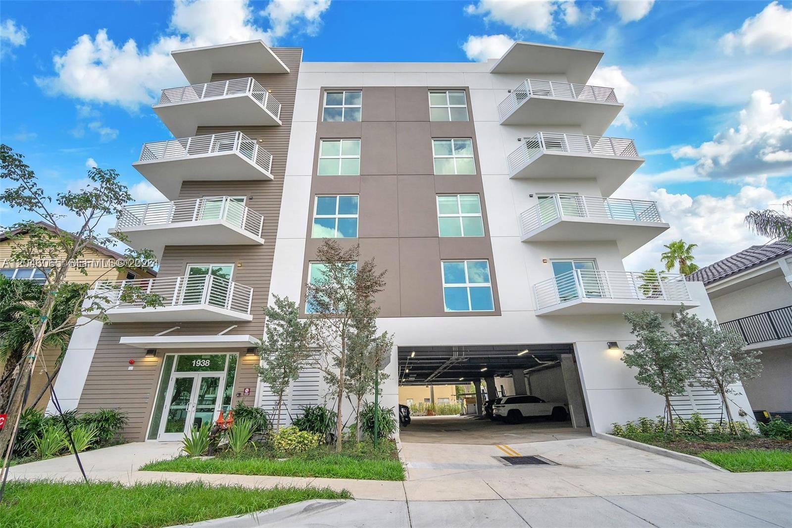A four-story modern apartment building features white balconies, brown siding, and a ground-level parking garage — 1938 Jackson St # 301, Hollywood FL 33020, HOLLYWOOD, FL