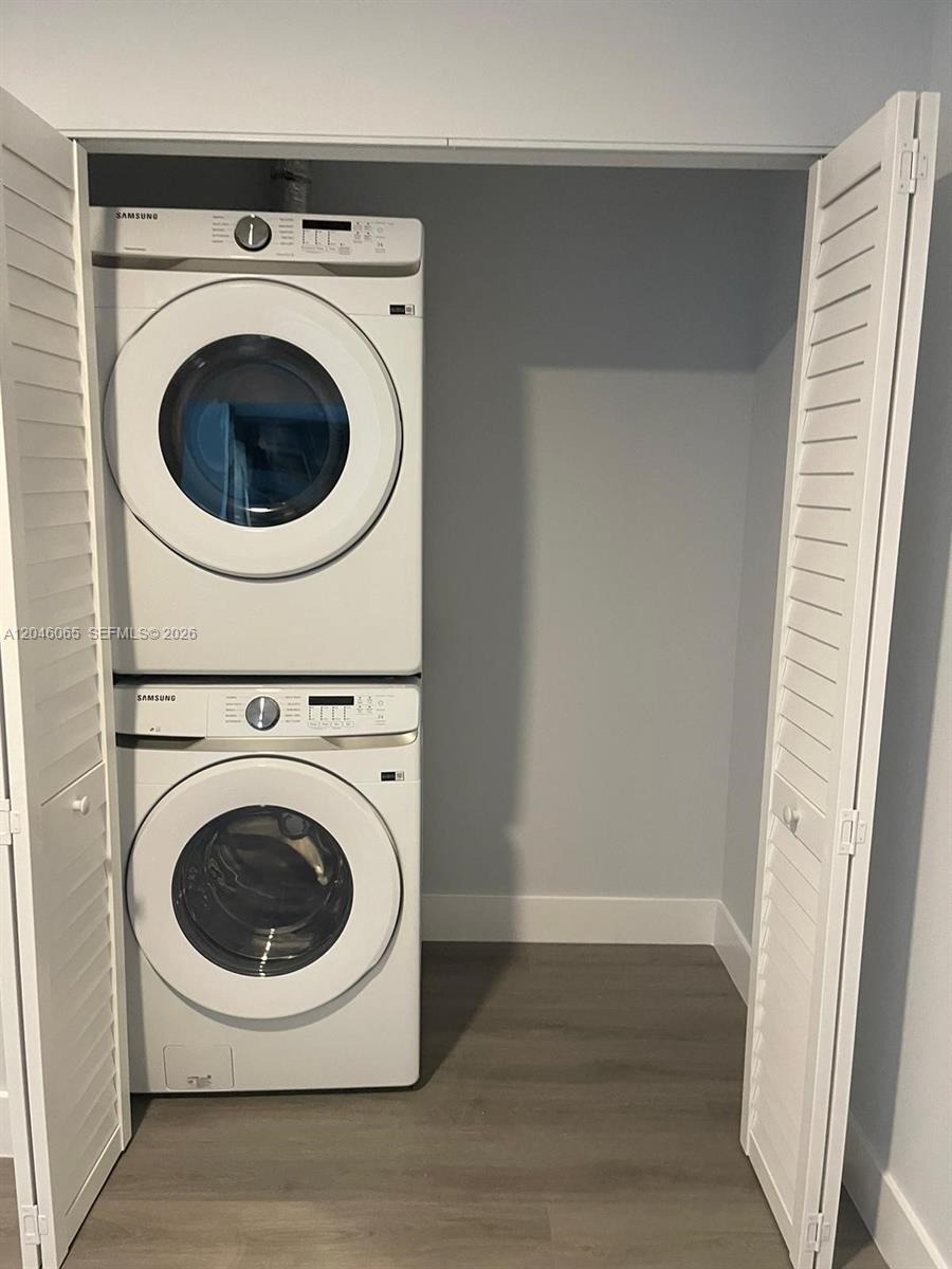 A stacked Samsung washer and dryer unit sits inside a closet with louvered doors — 1938 Jackson St # 301, Hollywood FL 33020, HOLLYWOOD, FL