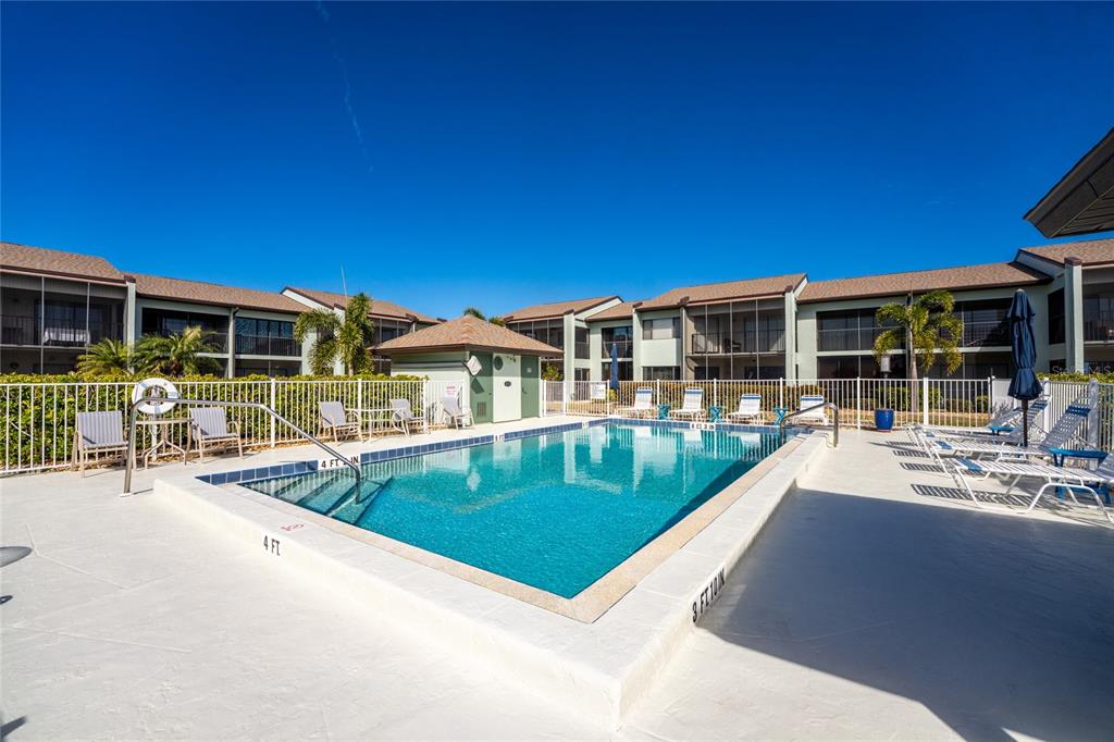 A rectangular swimming pool sits on a concrete deck surrounded by multi-story apartment buildings — 301 ISLAMORADA BOULEVARD UNIT 22B, PUNTA GORDA, FL
