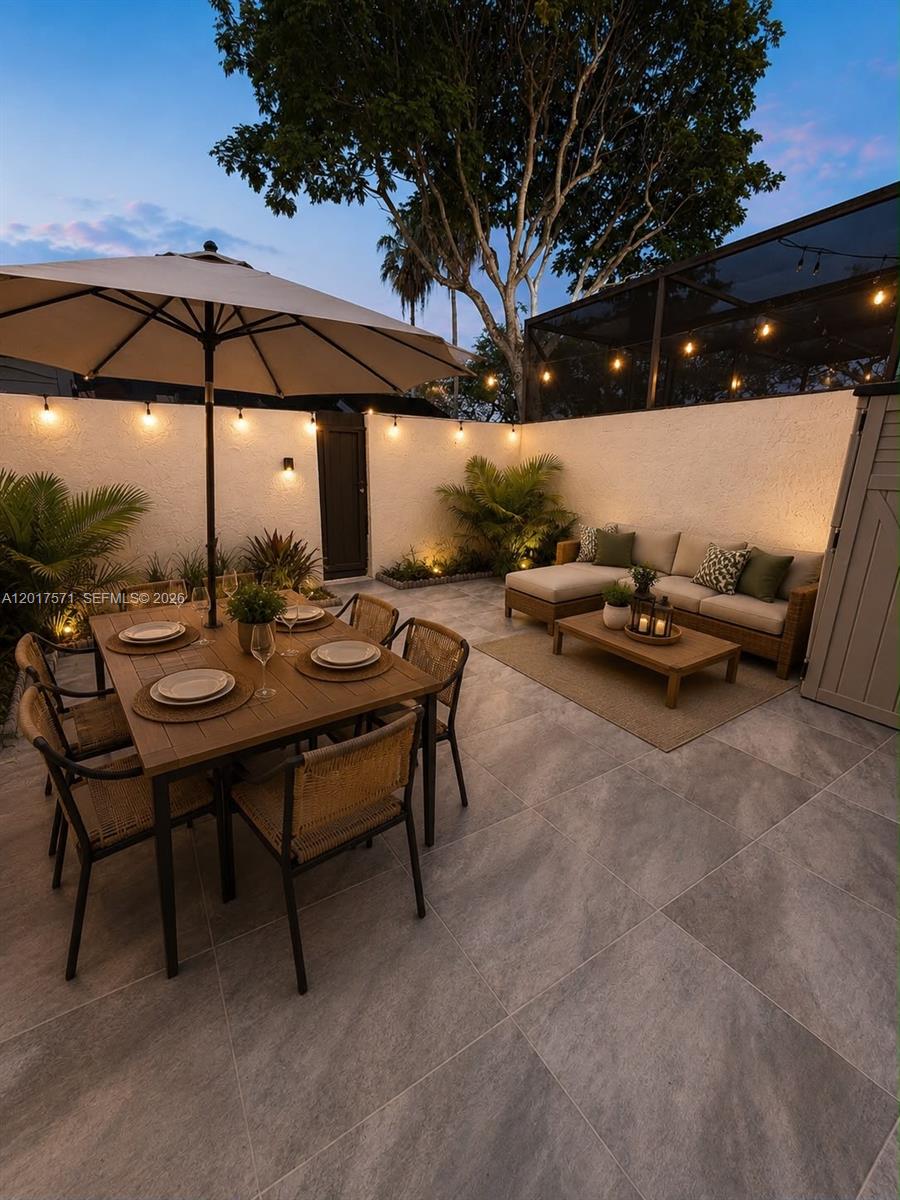An outdoor patio features a dining set, a sectional sofa, and string lights at dusk — 13380 SW 91st Ter, Miami FL 33186, MIAMI, FL