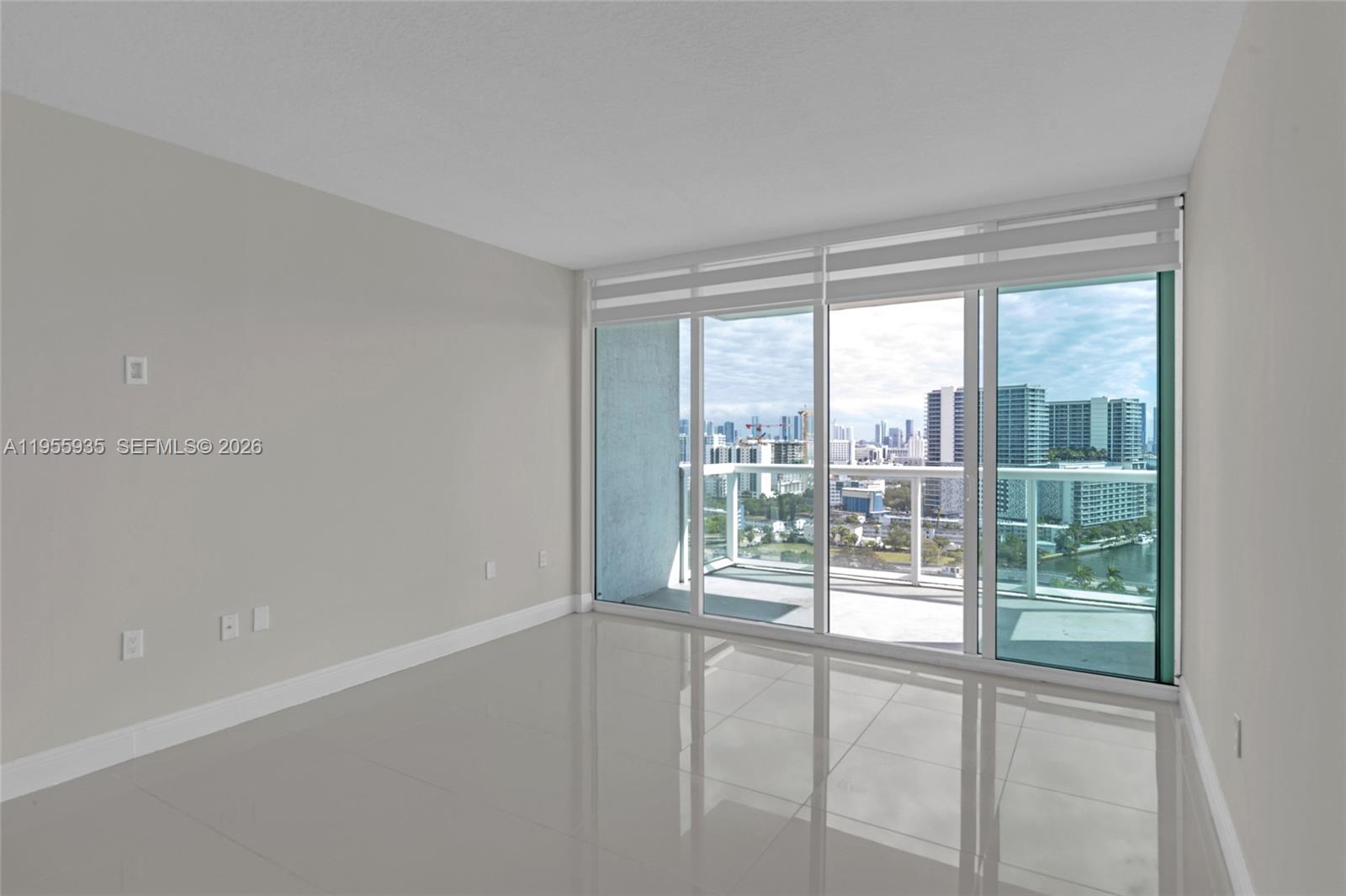 An empty room features light-colored tile flooring, plain walls, and a large sliding glass door — 1861 NW S River Dr # 2209, Miami FL 33125, MIAMI, FL