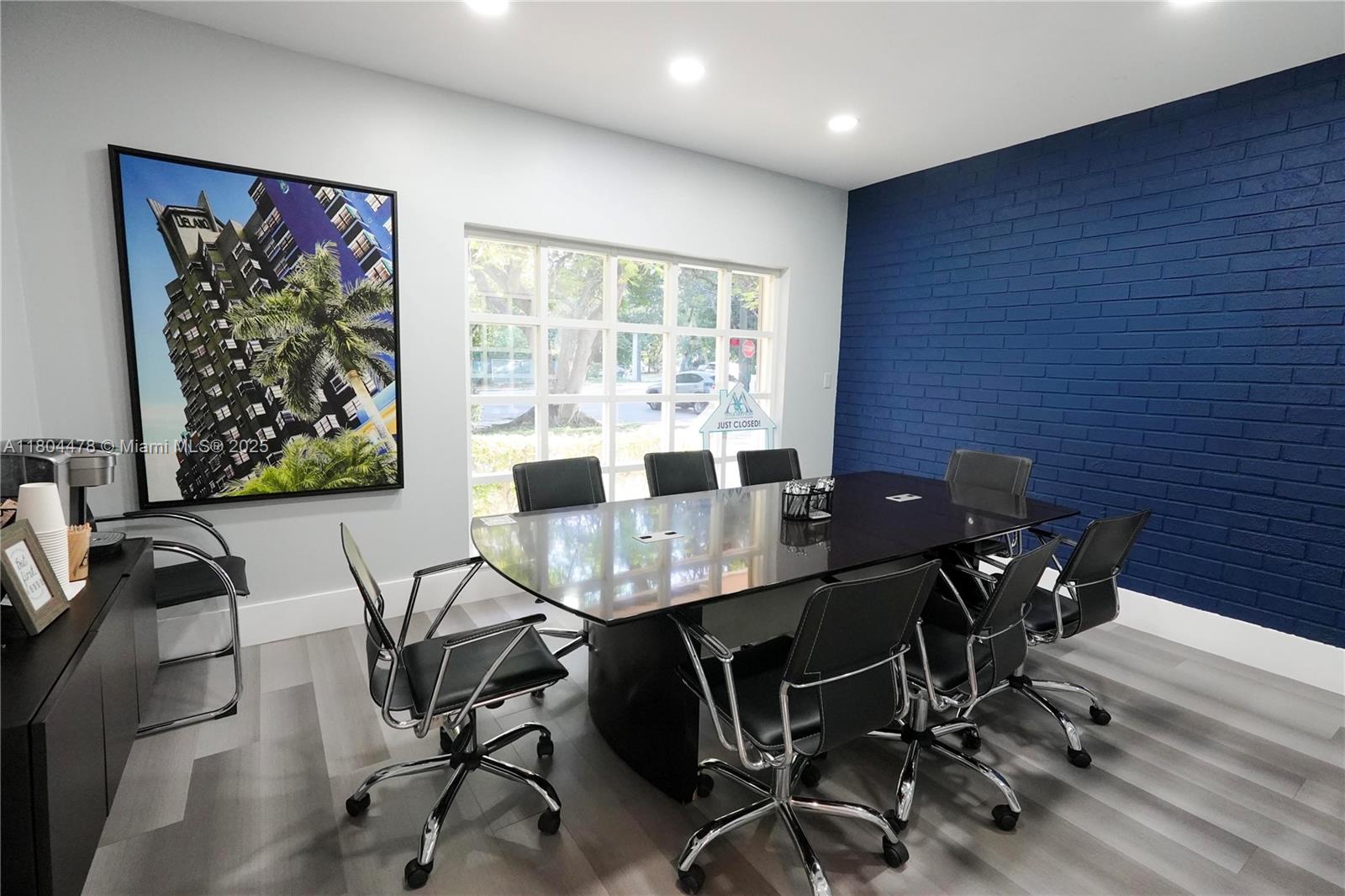 A conference room features a dark glass table, black chairs, and a navy brick wall — 8125 SW 120th St, Pinecrest FL 33156, PINECREST, FL