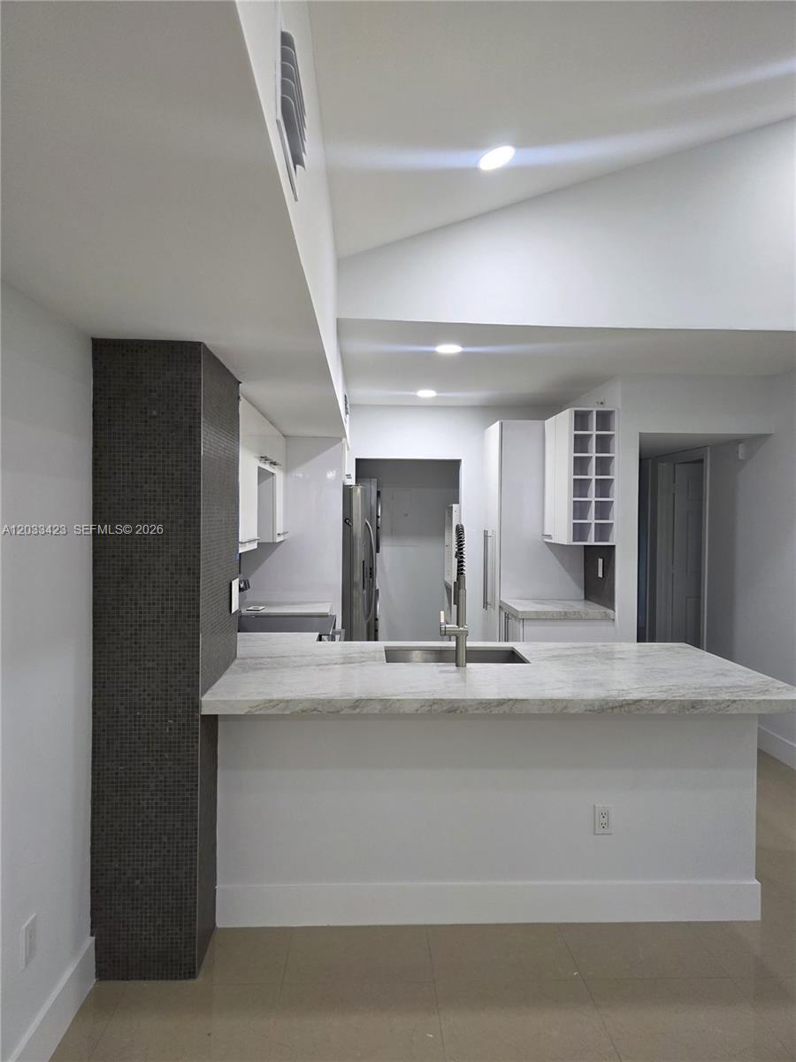 A kitchen features a stone-topped island with a sink, two stools, and light-colored cabinetry — 2600 S University Dr # 229, Davie FL 33328, DAVIE, FL