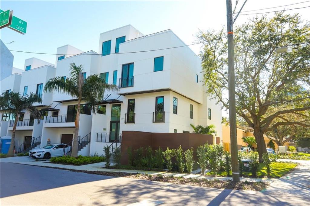 A modern white multi-story townhouse with a brown privacy wall and a palm tree — 2814 W BARCELONA STREET, TAMPA, FL