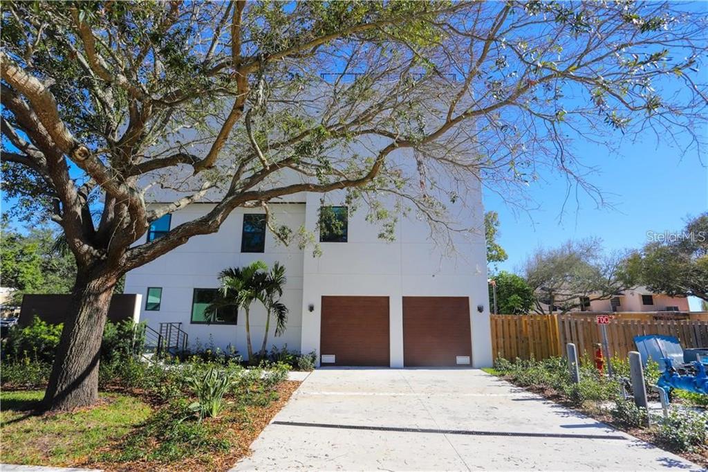 A modern white three-story building features two wooden garage doors and a concrete driveway — 2814 W BARCELONA STREET, TAMPA, FL