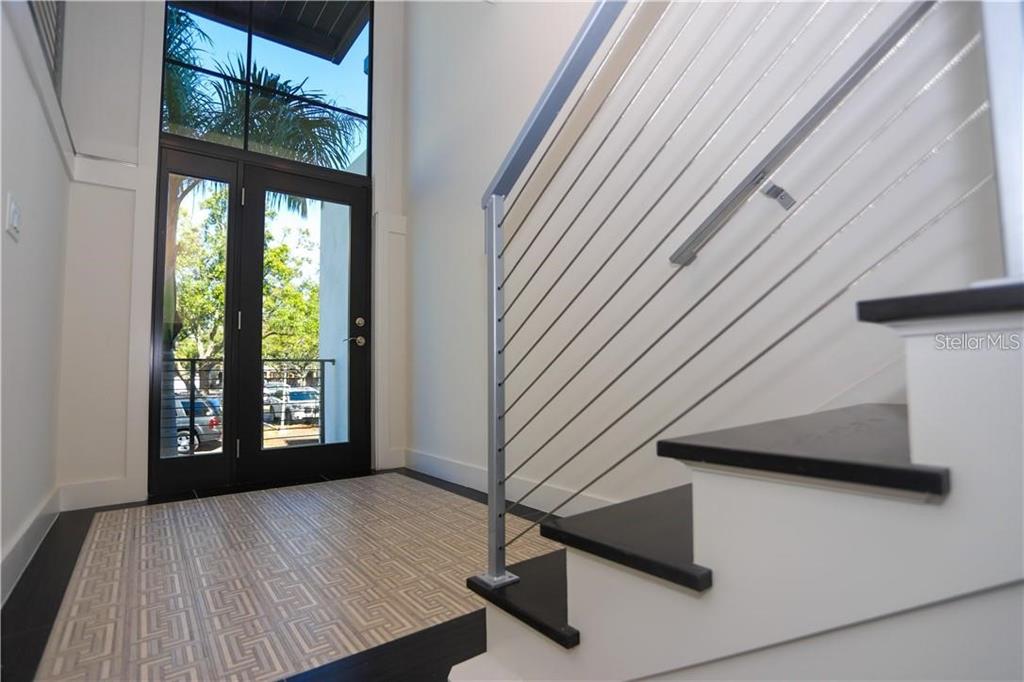 An entryway features a patterned tile floor, a glass-paneled door, and a modern cable-railing staircase — 2814 W BARCELONA STREET, TAMPA, FL