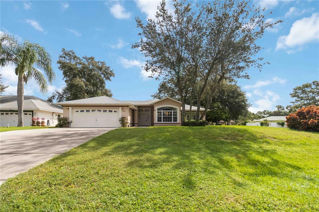 A single-story house with a two-car garage, a large front lawn, and mature trees — 2911 ELBERT WAY, KISSIMMEE, FL