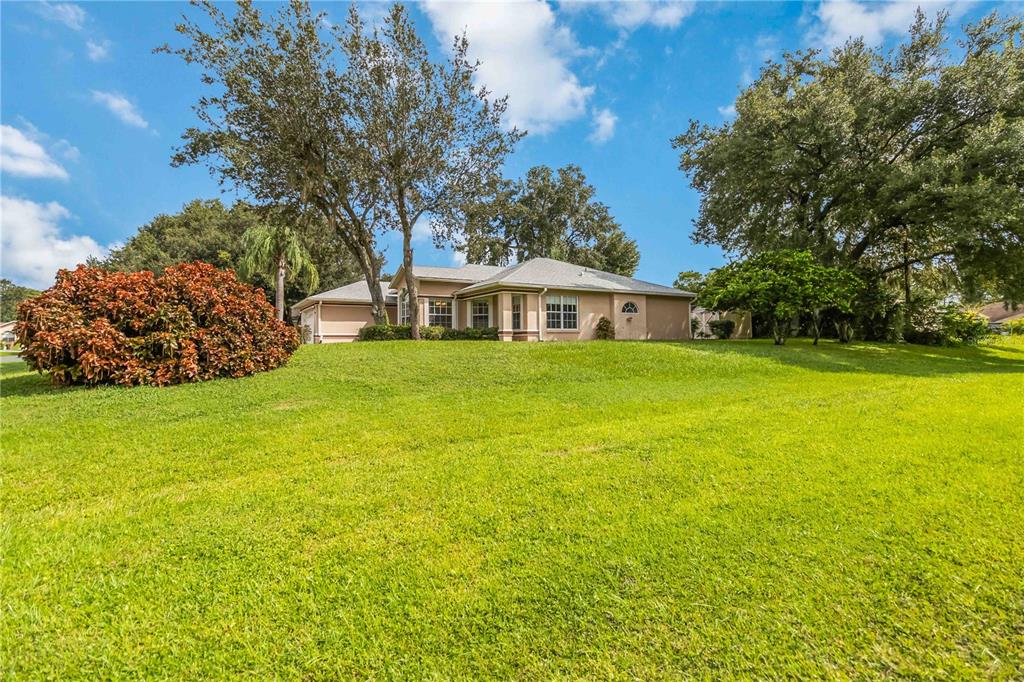 A single-story house with a tan exterior sits on a large, grassy, sloped lot — 2911 ELBERT WAY, KISSIMMEE, FL