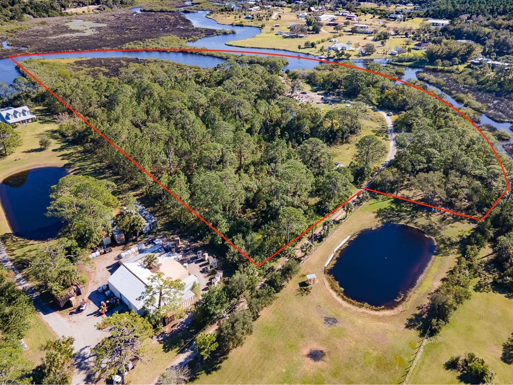 An aerial view shows a wooded lot outlined in red, bordered by water and fields — 1390 TUMBLIN DRIVE, NEW SMYRNA BEACH, FL