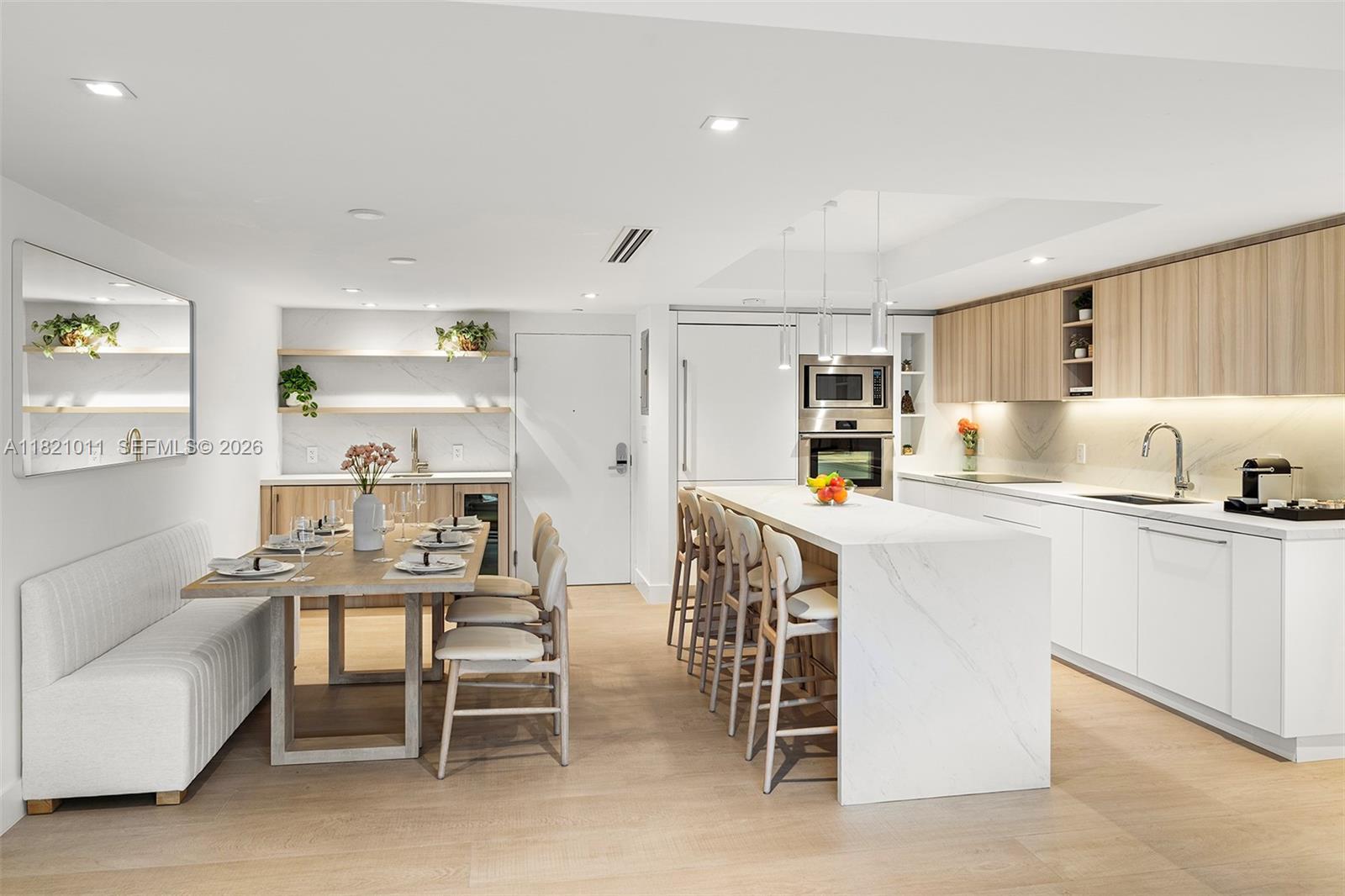 A modern open-concept kitchen features a marble island, light wood cabinetry, and an adjacent dining area — 2301 Collins Ave # 630, Miami Beach FL 33139, MIAMI BEACH, FL
