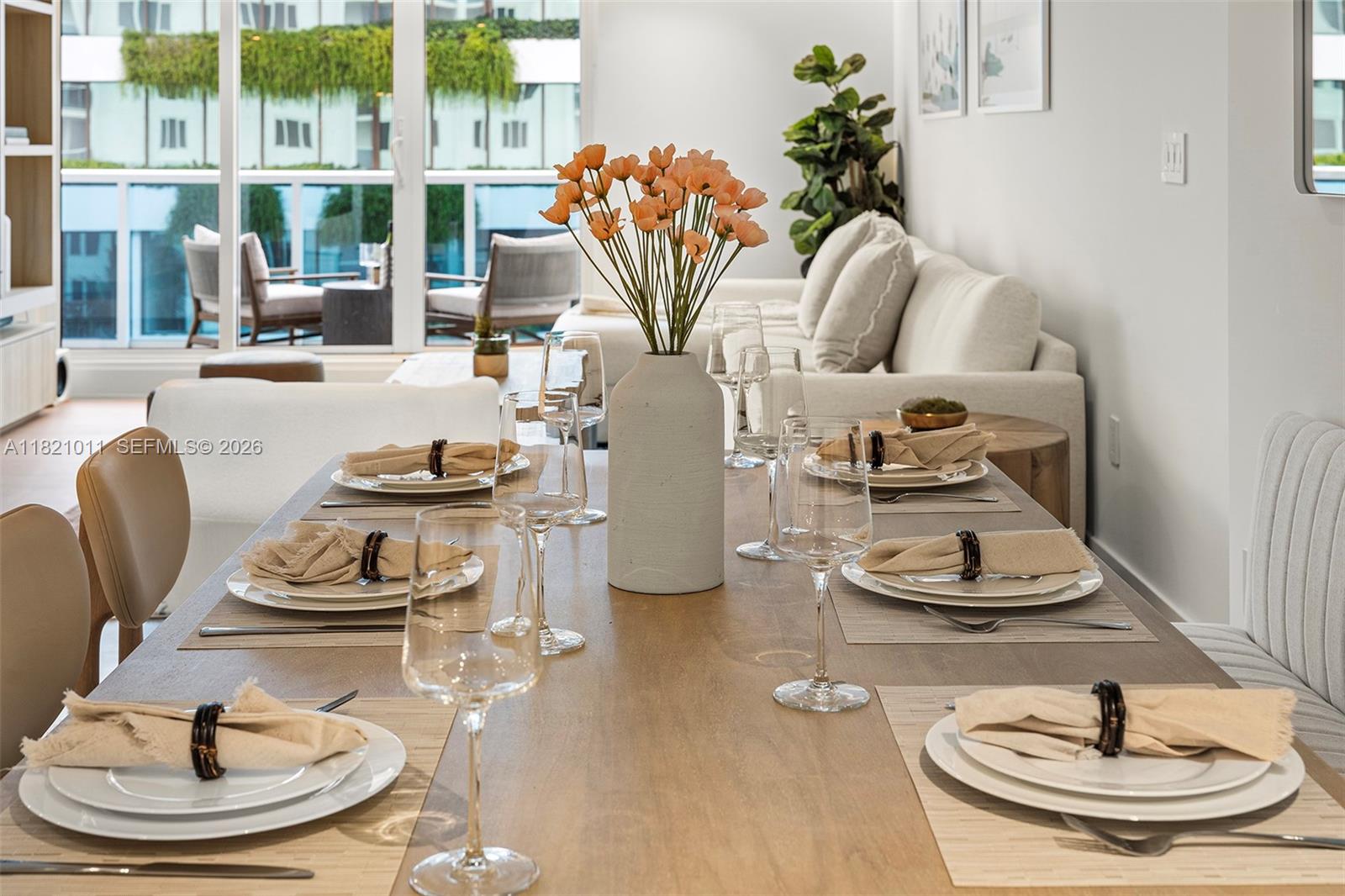 A dining table with place settings and a flower vase sits in a bright room — 2301 Collins Ave # 630, Miami Beach FL 33139, MIAMI BEACH, FL