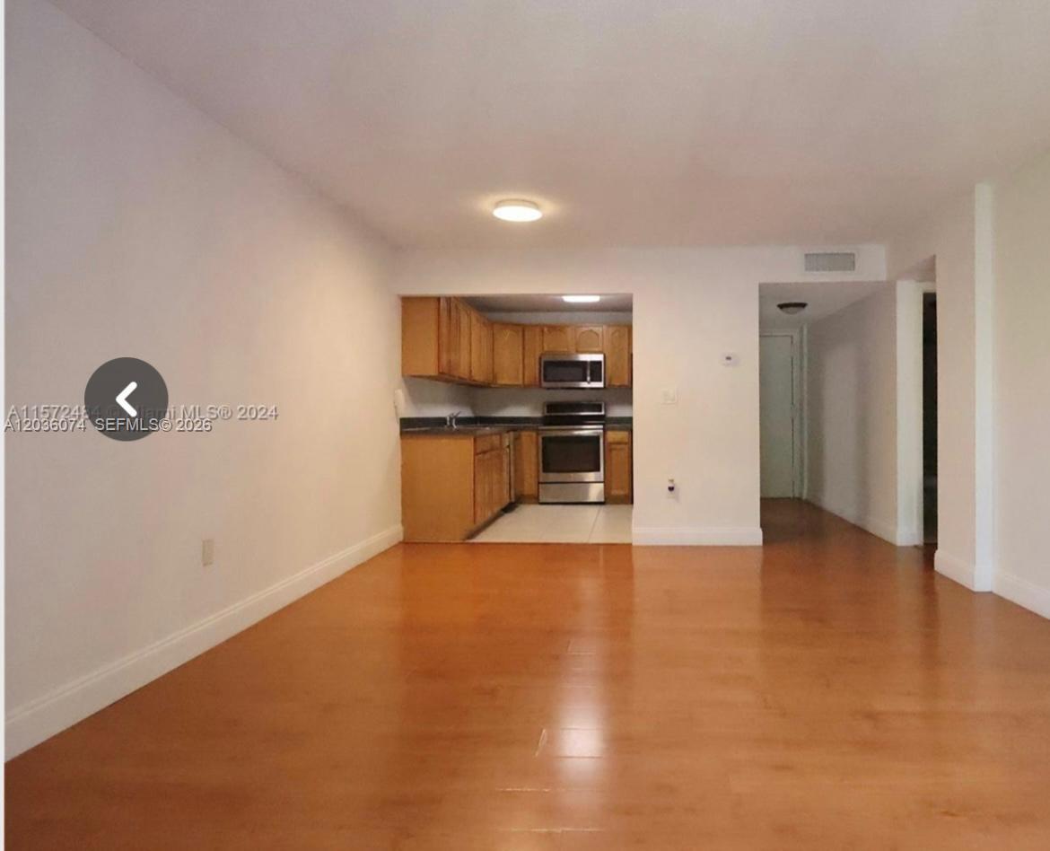 An open-concept living area with wood-look flooring leads to a kitchen with wood cabinets — 14250 SW 62nd St # 310, Miami FL 33183, MIAMI, FL