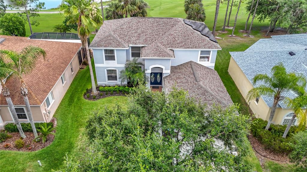 An aerial view shows a two-story house with a shingled roof and solar panels — 18109 KARA COURT, TAMPA, FL