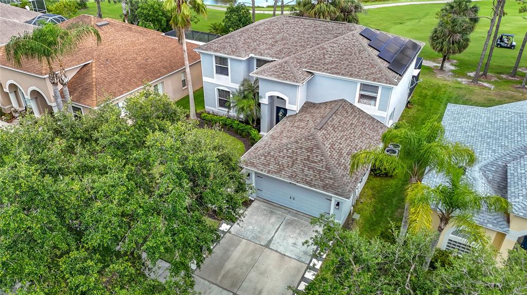 An aerial view shows a two-story house with a shingled roof and solar panels — 18109 KARA COURT, TAMPA, FL