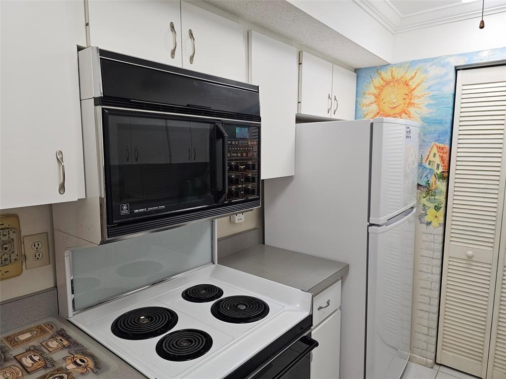 A dining room features a glass-topped table, upholstered chairs, a chandelier, and a mirrored wall — 4119 61ST AVENUE TERRACE W UNIT 404, BRADENTON, FL