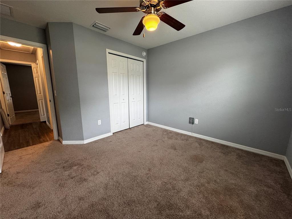 A bedroom features gray walls, brown carpeting, a ceiling fan, and white closet doors — 13705 SE 54TH COURT, SUMMERFIELD, FL