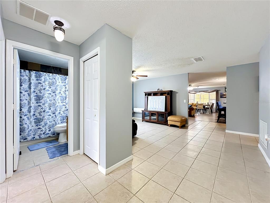 A tiled hallway leads to a bathroom with a blue shower curtain and a living area — 8307 LAINIE LANE, ORLANDO, FL
