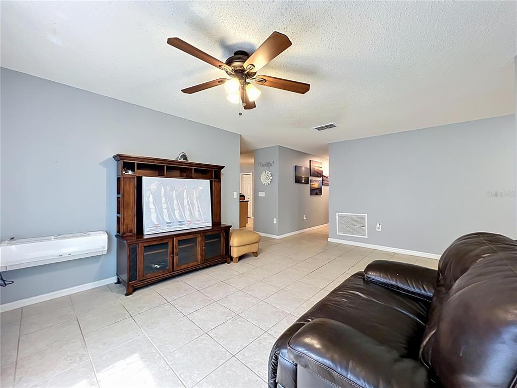 A living room features light gray walls, tile flooring, a ceiling fan, and a wooden entertainment center — 8307 LAINIE LANE, ORLANDO, FL