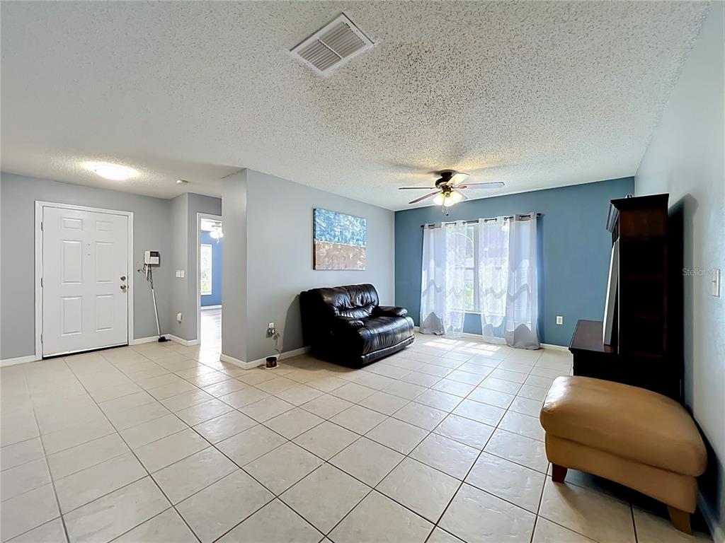 A living room features light blue walls, tile flooring, a leather sofa, and a ceiling fan — 8307 LAINIE LANE, ORLANDO, FL