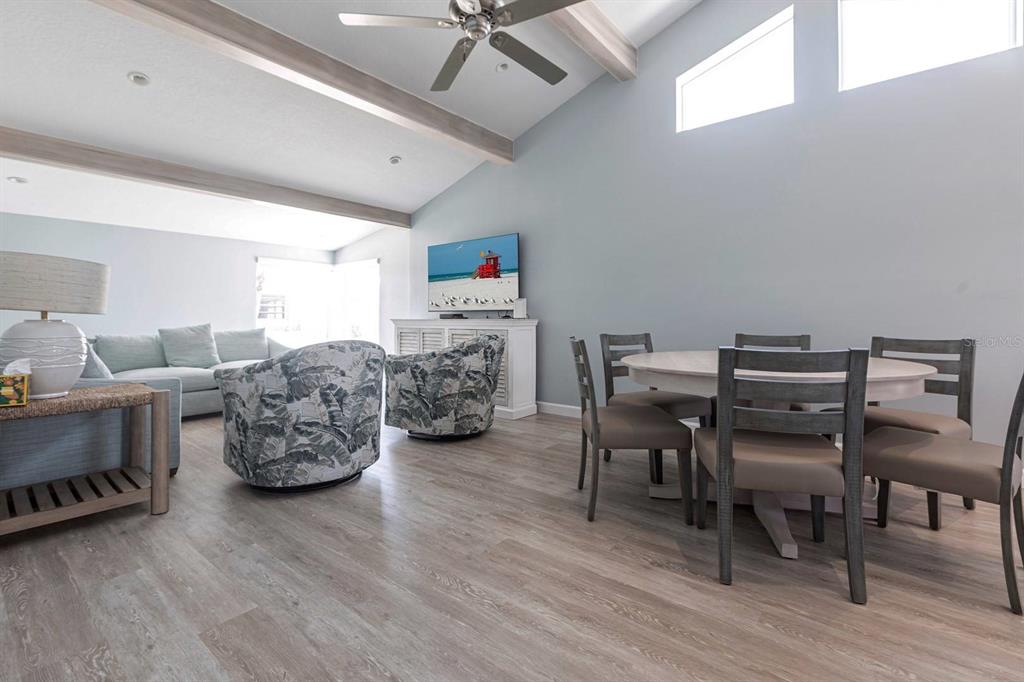 A living and dining area features light wood flooring, vaulted ceilings, and a ceiling fan — 6020 MIDNIGHT PASS ROAD UNIT 64, SARASOTA, FL
