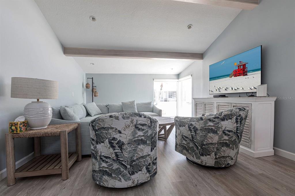 A living room features a sectional sofa, two patterned armchairs, and a wall-mounted television — 6020 MIDNIGHT PASS ROAD UNIT 64, SARASOTA, FL
